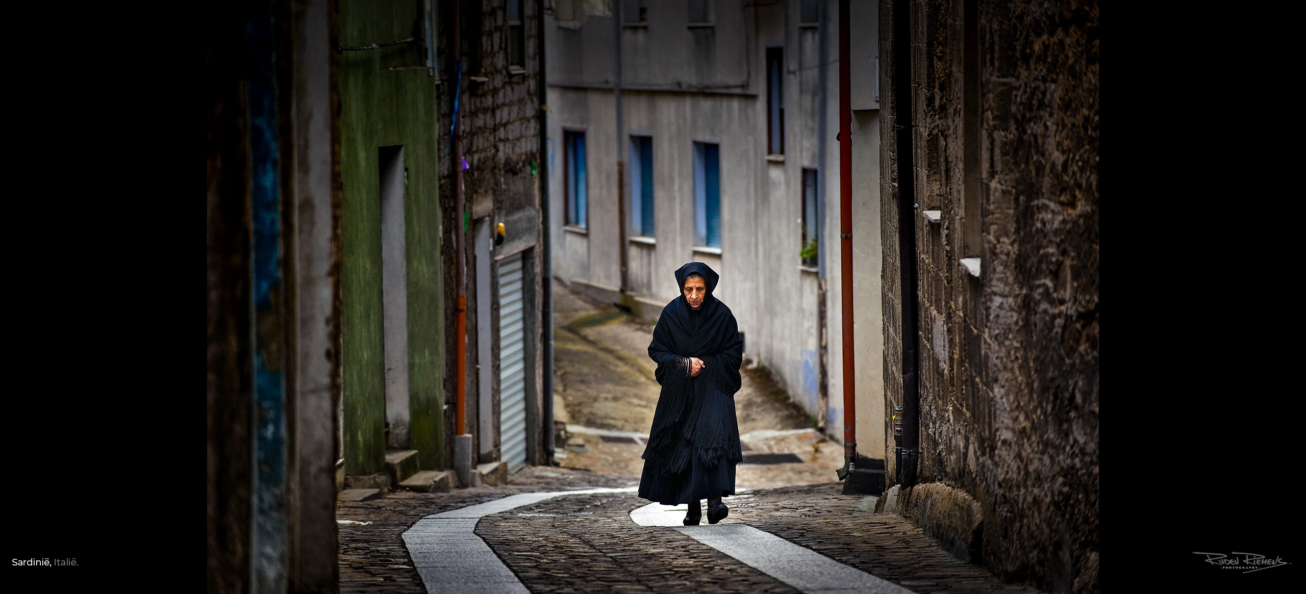 Weduwe in rouwkleding op weg naar de kerk in Sardinië Italië, Reisfotografie van Ruden Riemens Fotograaf.