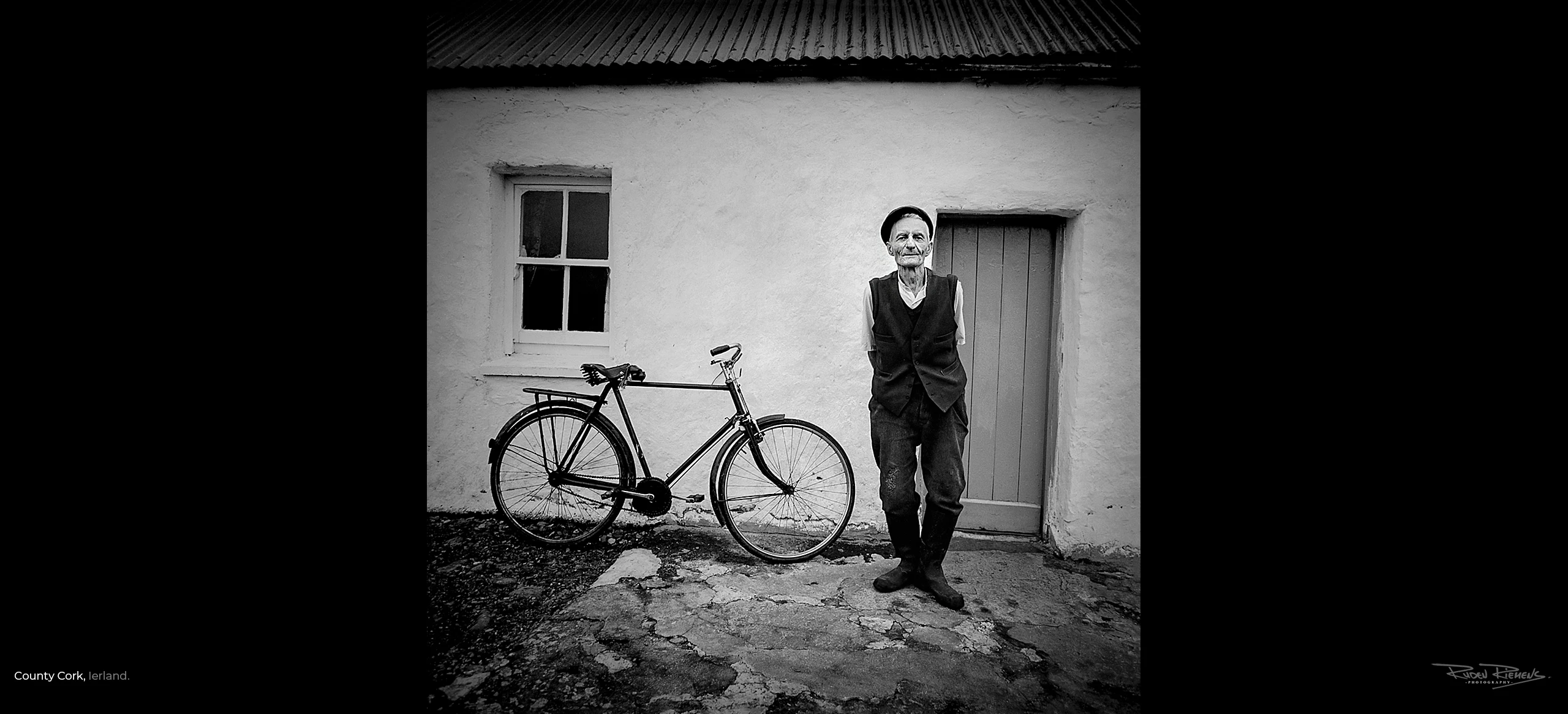 Oude Ierse man met fiets voor huis gefotografeerd in County Cork Ierland door Ruden Riemens Photography Onderweg.