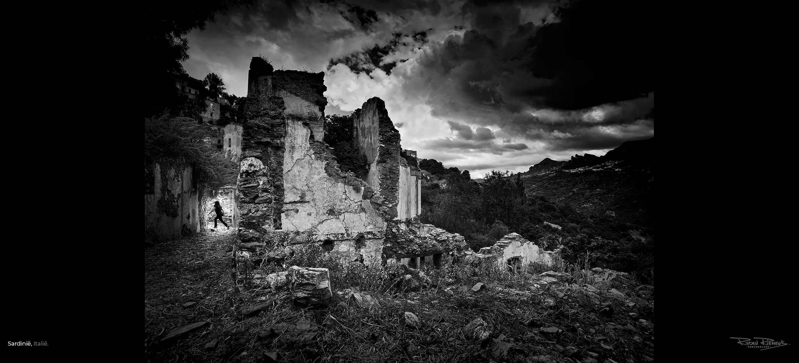 Zwart-wit foto van een rennende vrouw door verlaten dorp in Sardinië Italië, Ruden Riemens Fotografie.