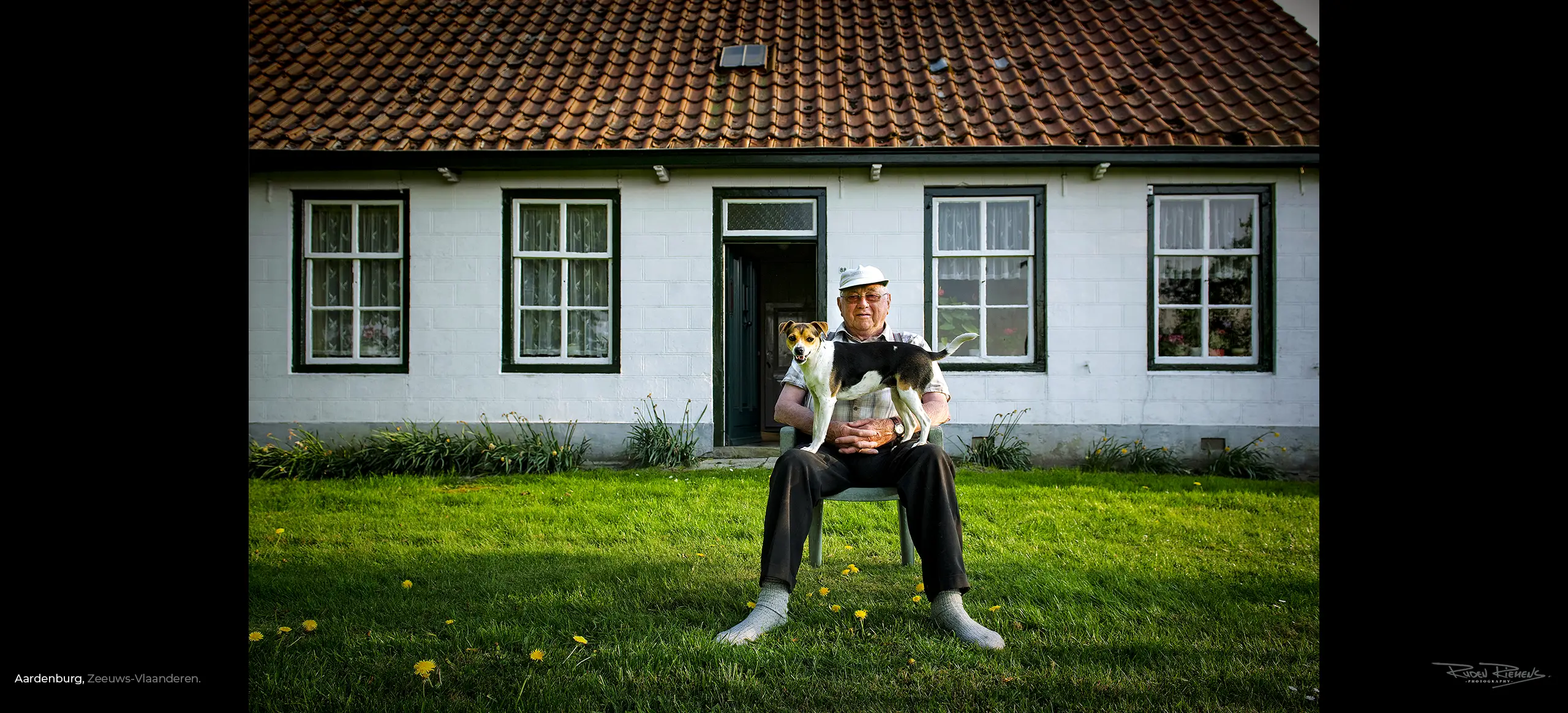 Portret van bewoner met hond op schoot in de tuin voor zijn huis in Aardenburg Zeeuws-Vlaanderen, Ruden Riemens Photography Zealand Color