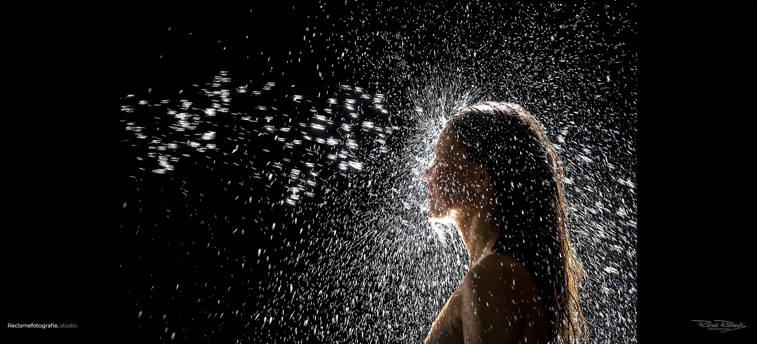 Jonge vrouw onder waterstraal, reclamefotografie door Ruden Riemens Fotografie voor badkamerleverancier.