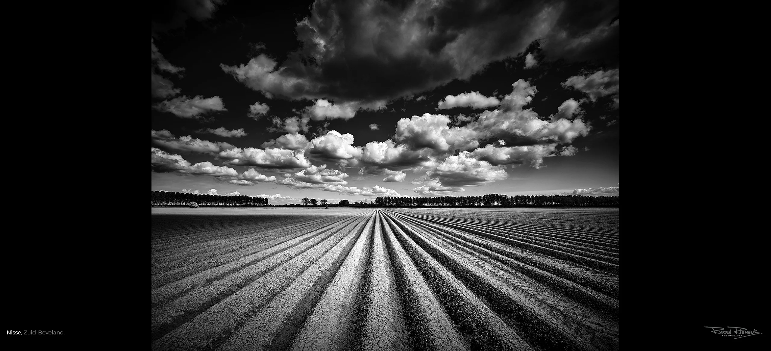 Foto van een Zeeuwse akker onder een prachtige Zeeuwse wolkenlucht in zwart-wit, gemaakt door de vakfotograaf Ruden Riemens.