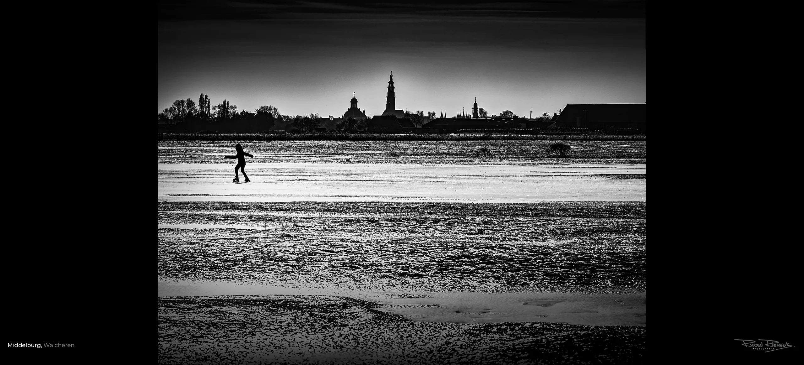 Winterse foto van schaatser op de akkers van Middelburg met het silhouet van de Oostkerk, Lange Jan en Stadhuis op de achtergrond, weer zo'n prachtige foto van Ruden Riemens.