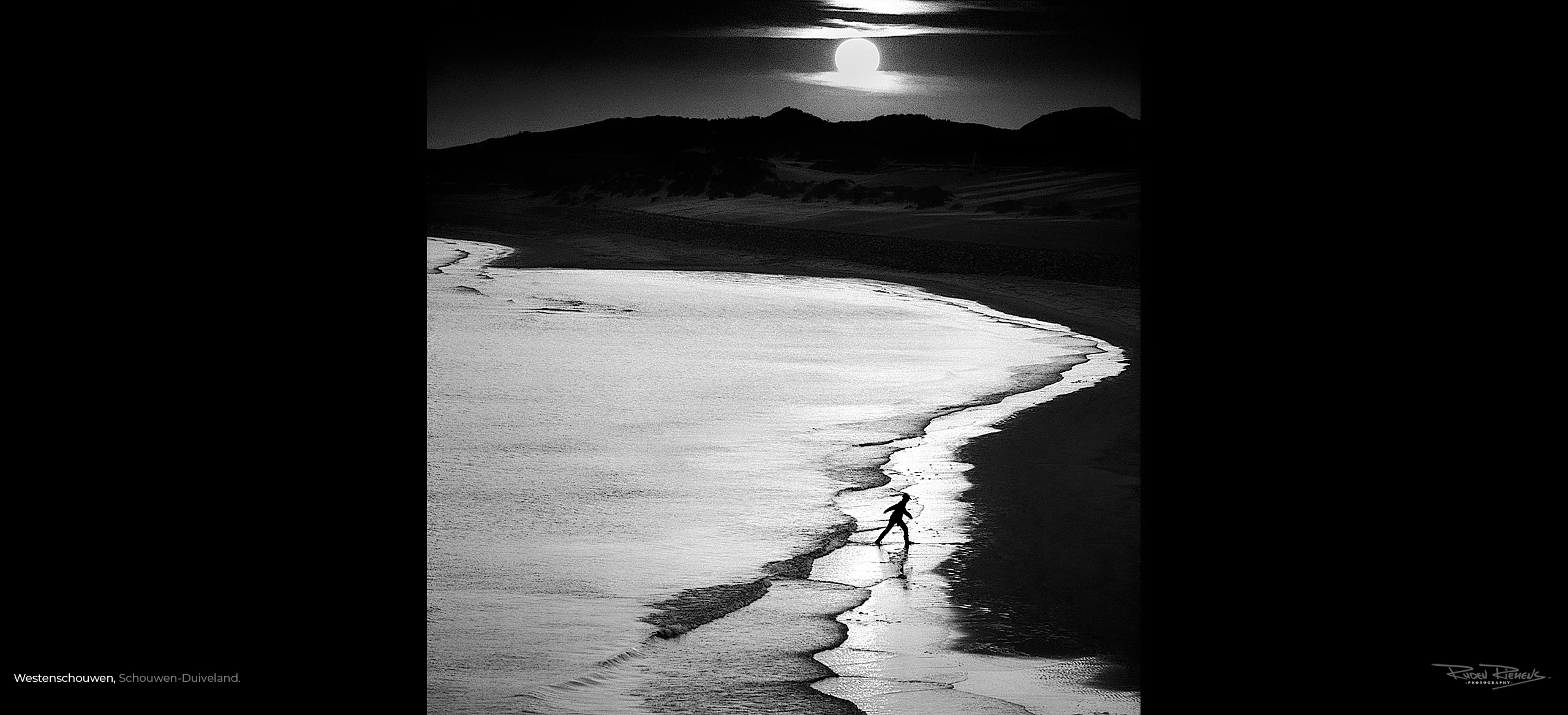 Silhouet van wandelaar in zee met ondergaande zon te Westenschouwen in Schouwen-Duiveland, foto Ruden Riemens.