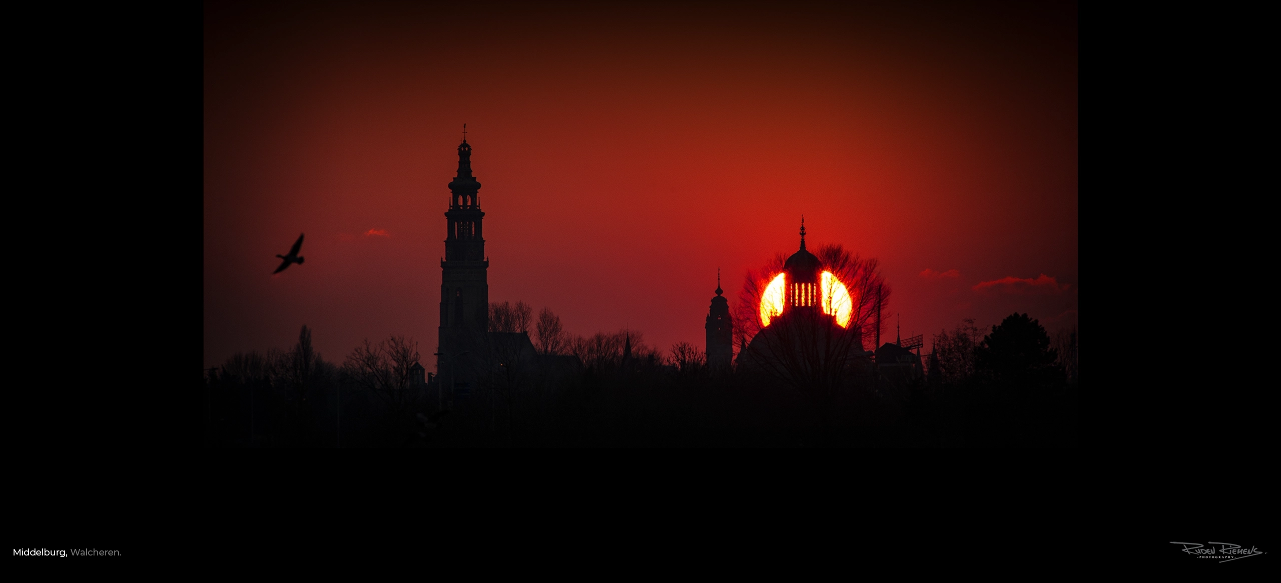 Het silhouet van Middelburg bij ondergaande zon in een rode avondlucht, gefotografeerd door Ruden Riemens fotograaf.