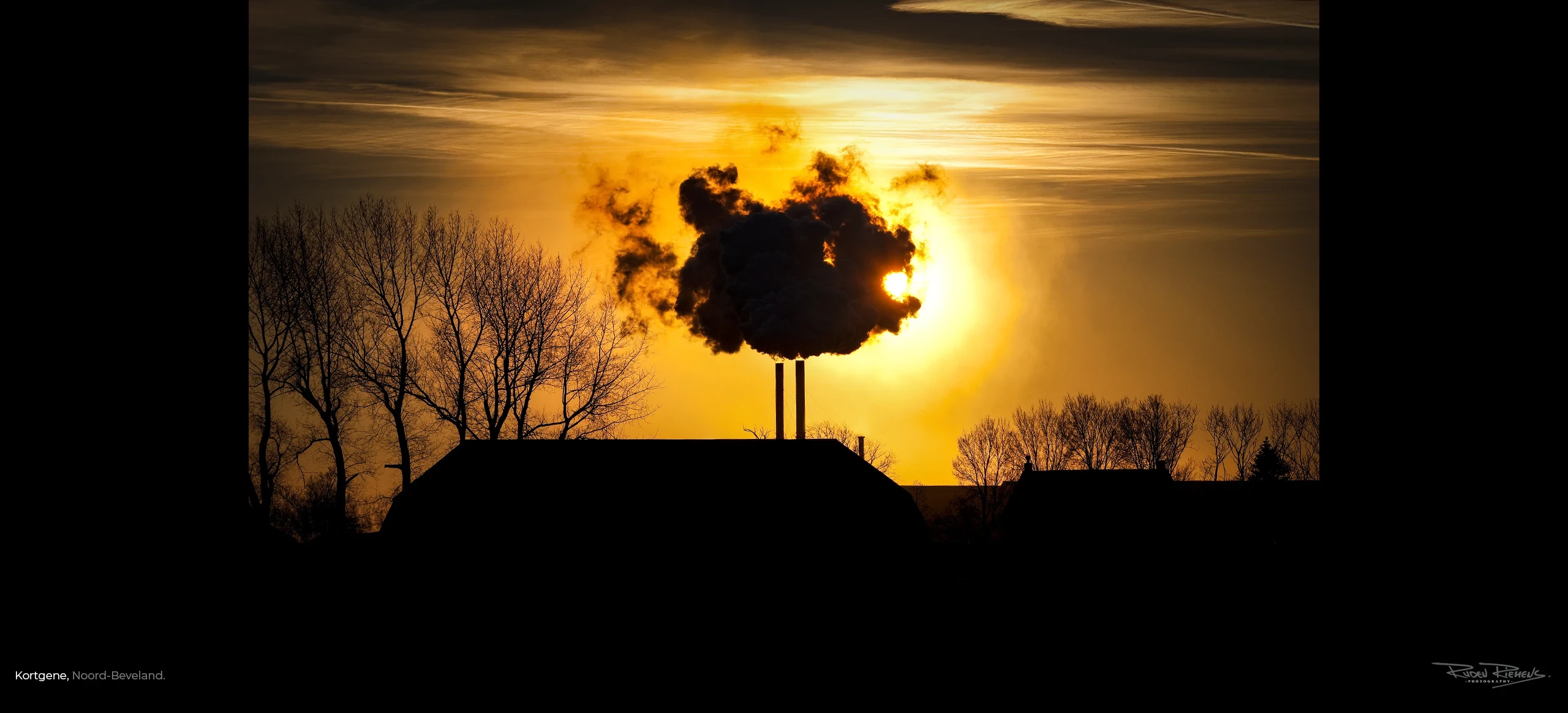 Rookwolken uit de schoorstenen van de grasdrogerij in Kortgene Zeeland tegen een gouden avondzon, Ruden Riemens Photography.